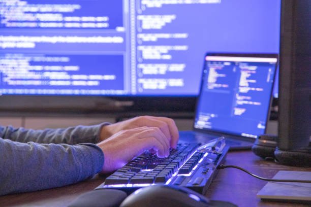 He works in a home office and is illuminated by the computer screens - Kanineetech System Solutions All-in-one IT Web development